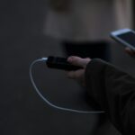 a person holding a cell phone and a charger