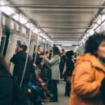 woman standing inside train surrounded by people
