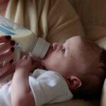 a woman feeding a baby with a bottle of milk