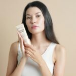 Woman holding a tube of facial cleanser
