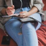 person in blue denim jeans holding white tablet computer